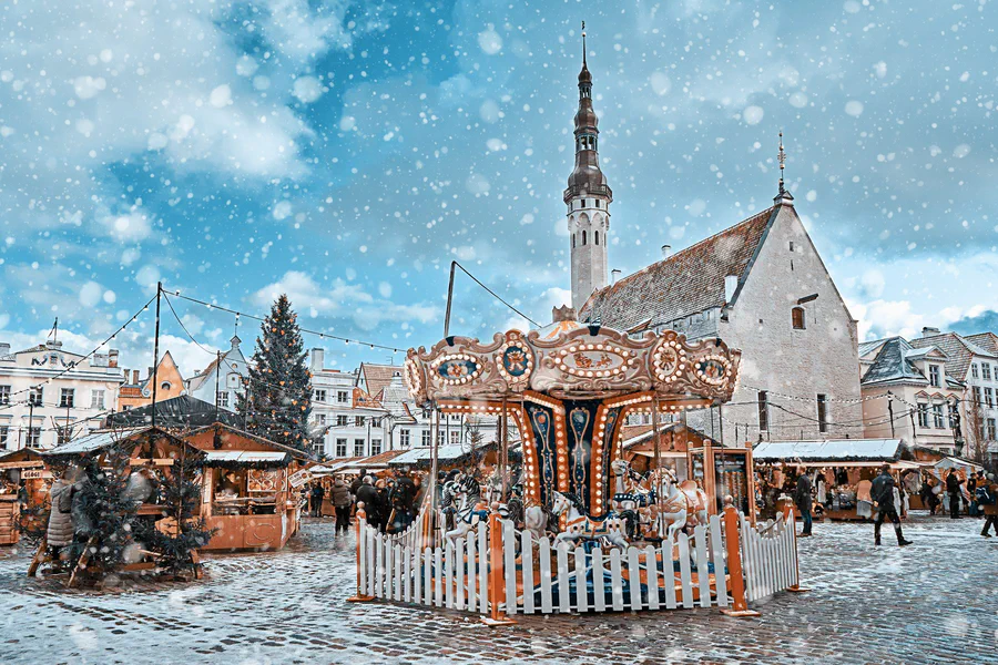 La plaza del Ayuntamiento de Tallin nevada, con un árbol de Navidad alto y casetas de madera del mercadillo