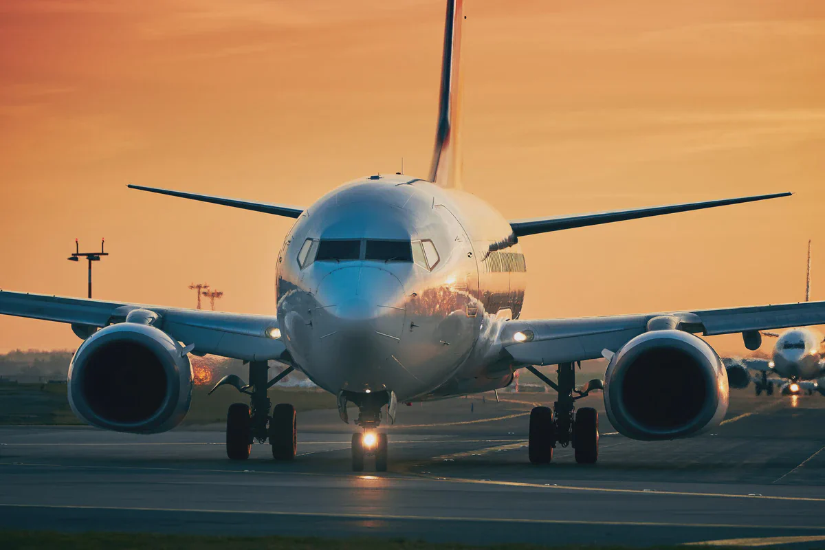 Airliner taxiing head-on at sunset with another aircraft queued behind it