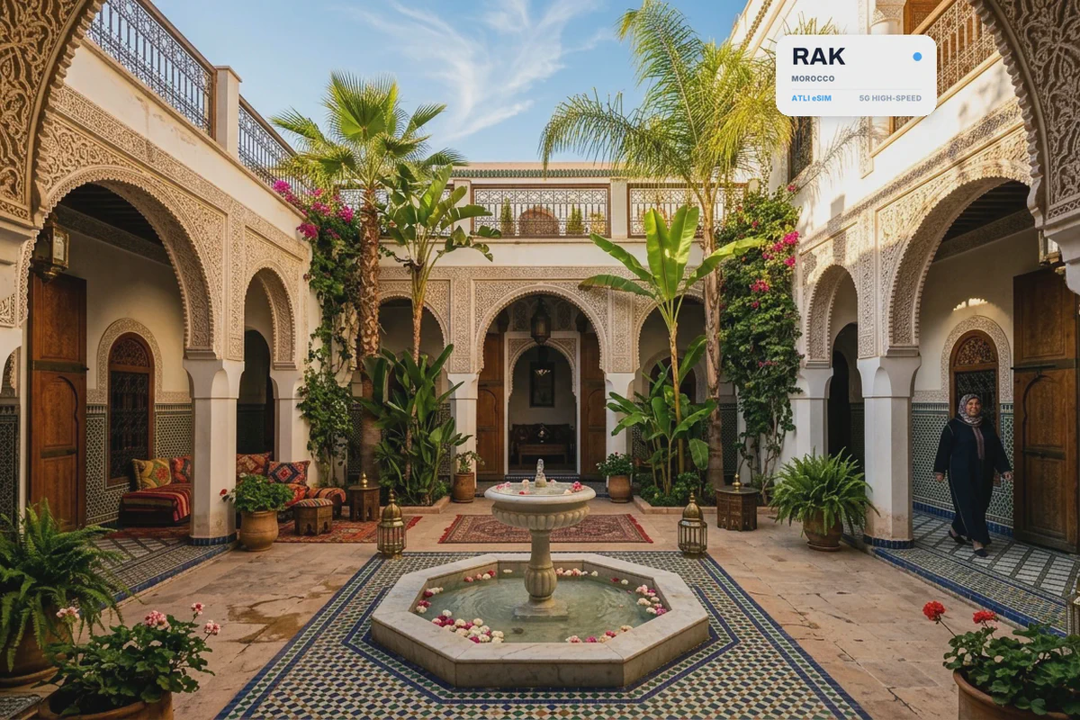 Il cortile piastrellato di un riad a Marrakech, con una fontana, con una scheda eSIM Atli che mostra il codice aeroportuale RAK