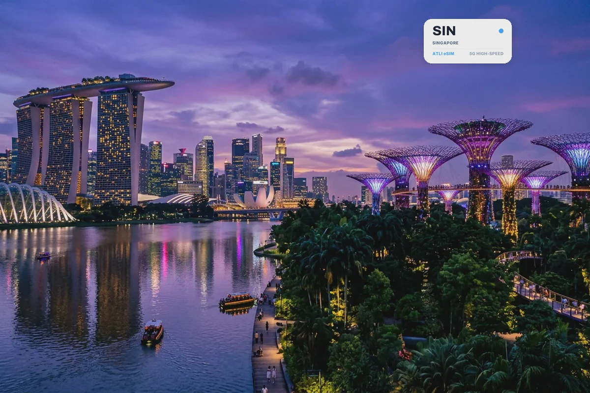 Marina Bay e i Supertree illuminati al crepuscolo, con una scheda eSIM Atli che mostra il codice aeroportuale SIN
