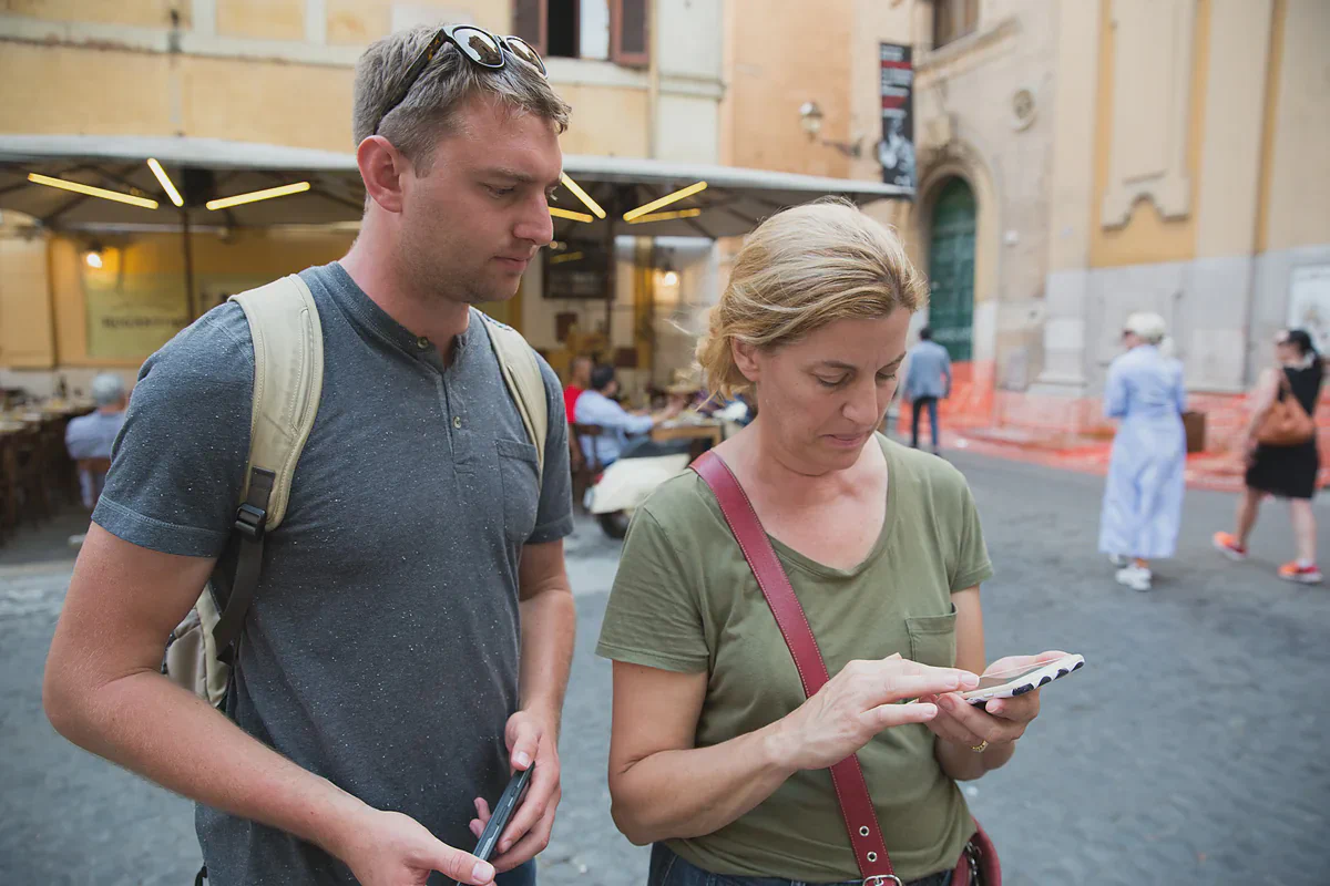 Dois viajantes olhando um celular numa rua na Itália