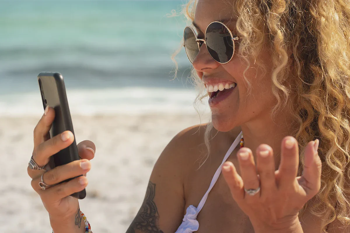 Una donna ride al telefono in spiaggia
