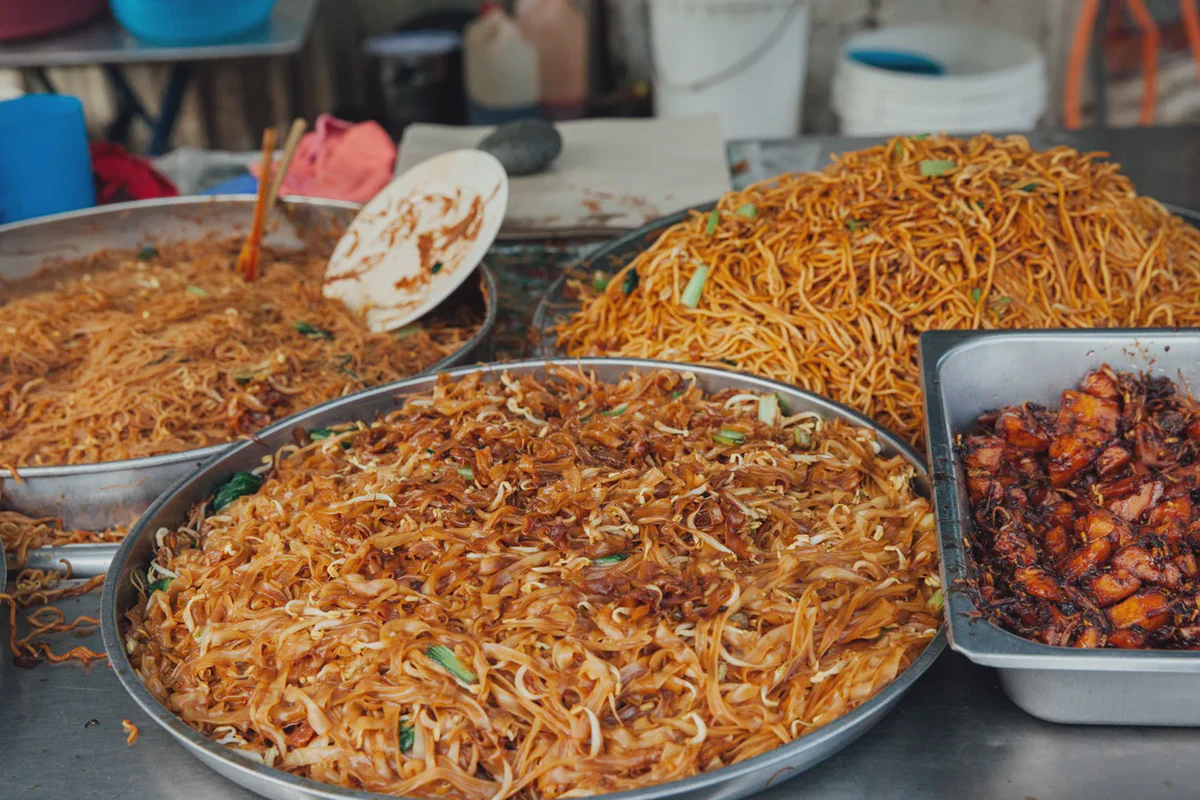 Vassoi di kway teow fritto e noodles su una bancarella di George Town