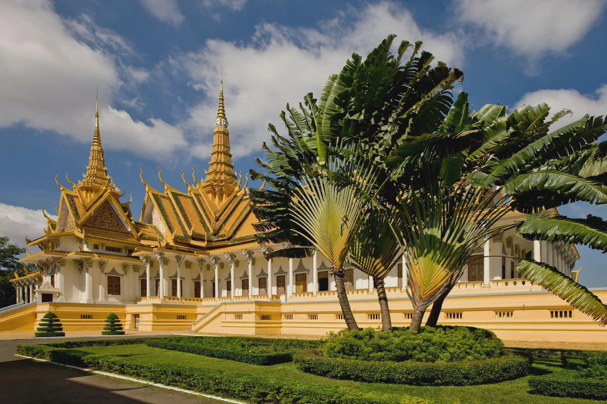 Die goldenen Türme der Thronhalle des Königspalasts in Phnom Penh hinter Palmen